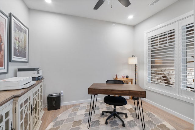 home office with light hardwood / wood-style flooring and ceiling fan