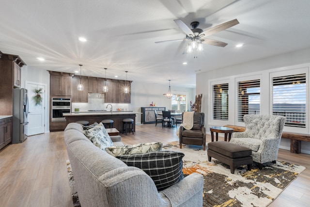 living room with ceiling fan, sink, and light hardwood / wood-style flooring