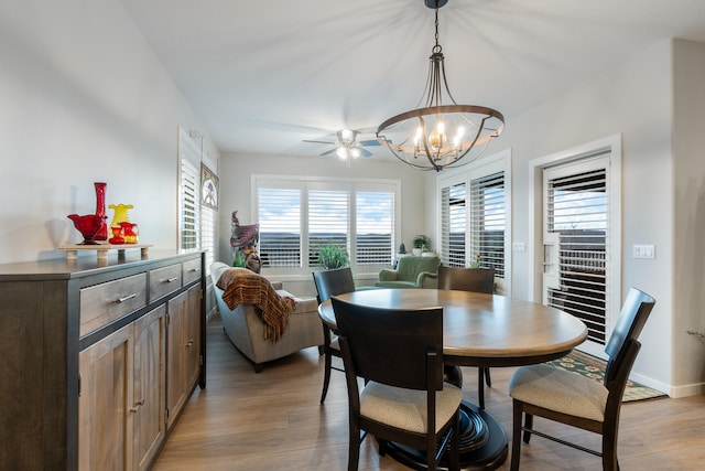 dining space with ceiling fan with notable chandelier, light wood-type flooring, and a healthy amount of sunlight