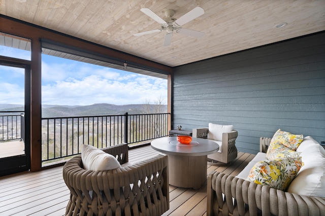 sunroom featuring a mountain view, ceiling fan, and wood ceiling