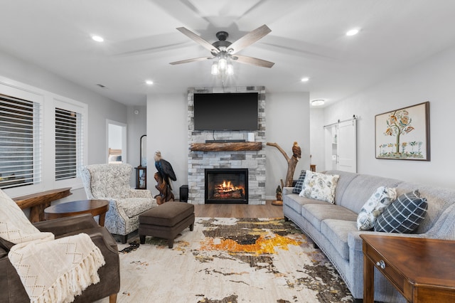 living room with a fireplace, hardwood / wood-style floors, a barn door, and ceiling fan