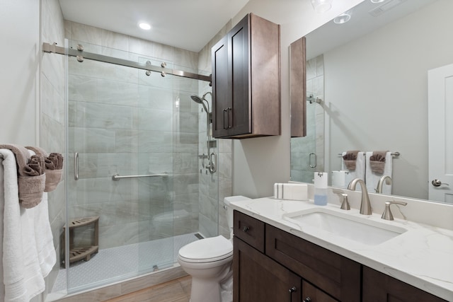 bathroom featuring vanity, a shower with shower door, and toilet