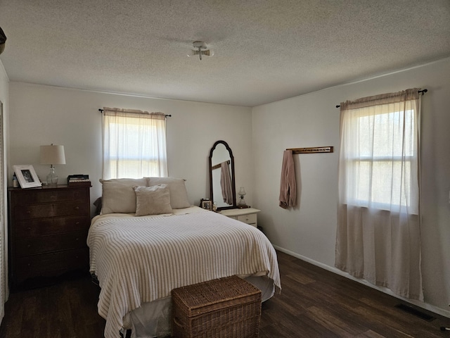 bedroom featuring a textured ceiling, dark hardwood / wood-style floors, and multiple windows