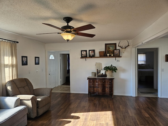 living room featuring ceiling fan, a textured ceiling, and dark wood-type flooring