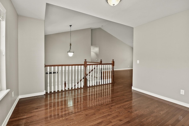 spare room with vaulted ceiling and dark wood-type flooring