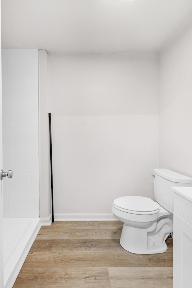 bathroom with walk in shower, hardwood / wood-style flooring, vanity, and toilet