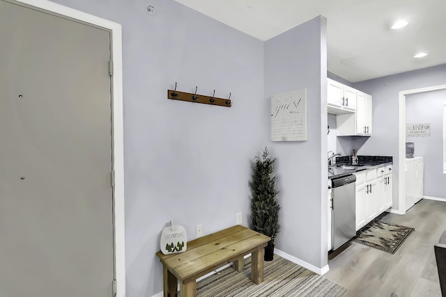 kitchen with light hardwood / wood-style flooring, white cabinets, stainless steel dishwasher, and sink