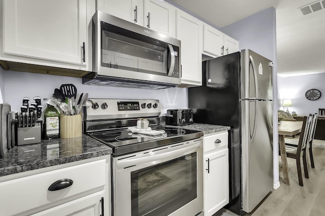 kitchen featuring white cabinets, light hardwood / wood-style floors, appliances with stainless steel finishes, and dark stone counters