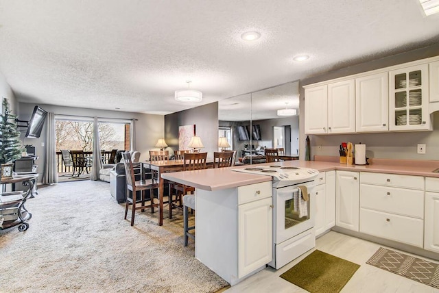 189 Avondale Dr Unit 91-6, Branson, MO 65616 - kitchen featuring white range with electric stovetop, kitchen peninsula, light colored carpet, a textured ceiling, and a kitchen bar
