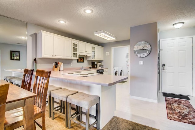 189 Avondale Dr Unit 91-6, Branson, MO 65616 - kitchen with washing machine and dryer, kitchen peninsula, a textured ceiling, a kitchen bar, and white cabinets