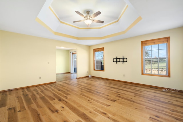 spare room featuring hardwood / wood-style floors, ceiling fan, and a raised ceiling