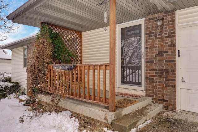 snow covered property entrance with covered porch