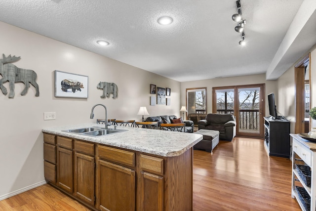 kitchen featuring a textured ceiling, kitchen peninsula, sink, and light hardwood / wood-style flooring