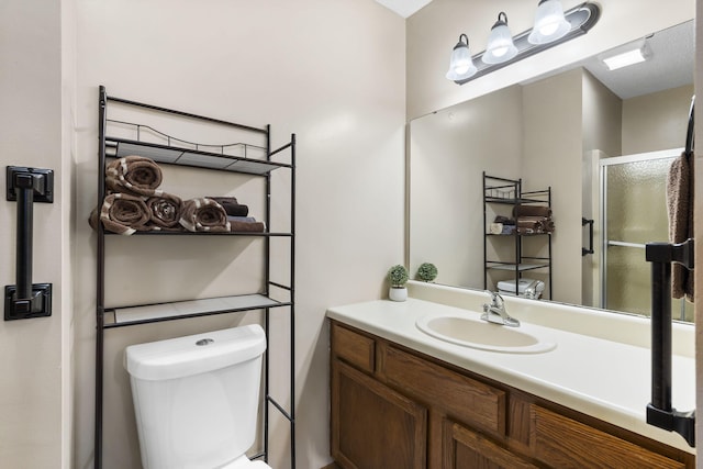 bathroom featuring vanity, an enclosed shower, and toilet