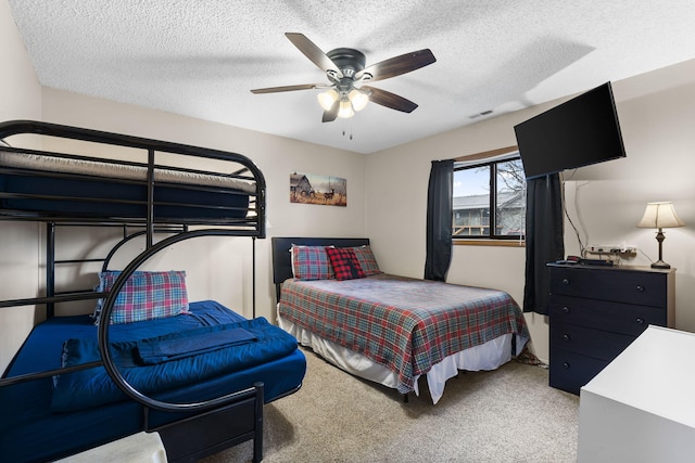 bedroom with ceiling fan, carpet floors, and a textured ceiling