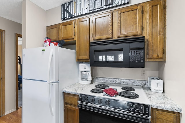 kitchen featuring black appliances, a textured ceiling, and wood-type flooring