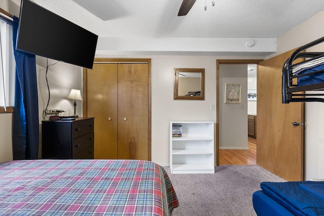 carpeted bedroom with ceiling fan, a textured ceiling, and a closet