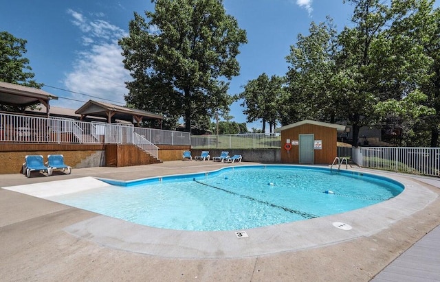 view of swimming pool with a patio area and a shed