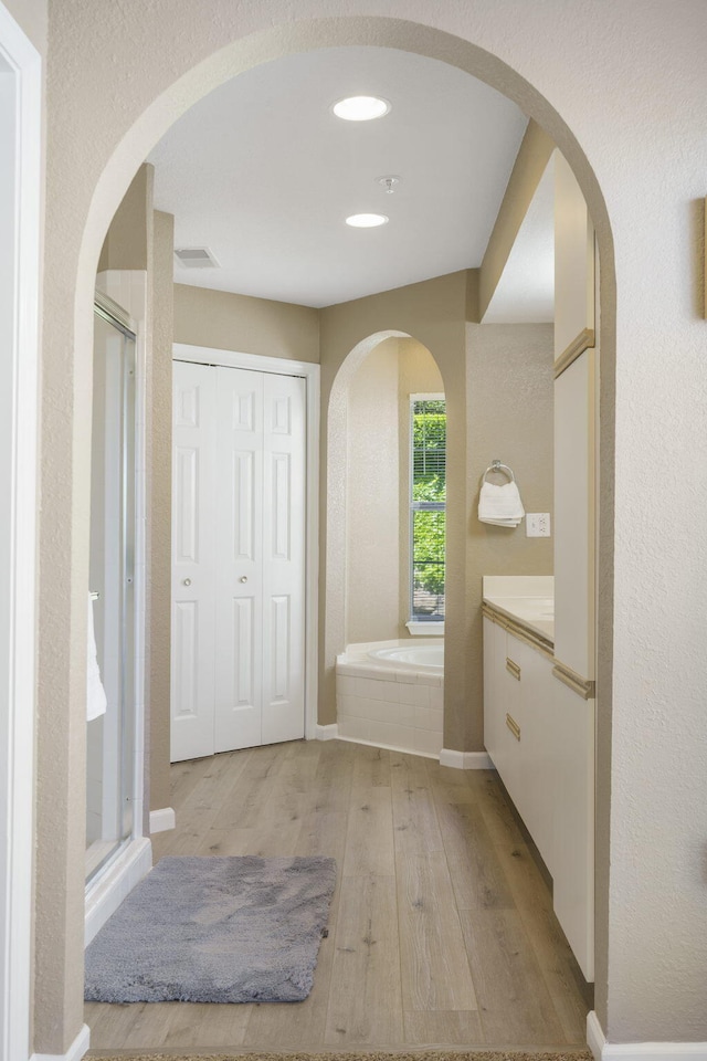 bathroom with wood-type flooring, vanity, and independent shower and bath