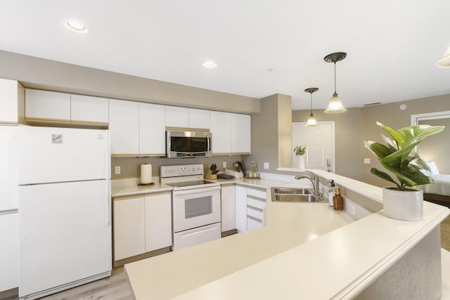 kitchen featuring sink, hanging light fixtures, kitchen peninsula, white appliances, and white cabinets