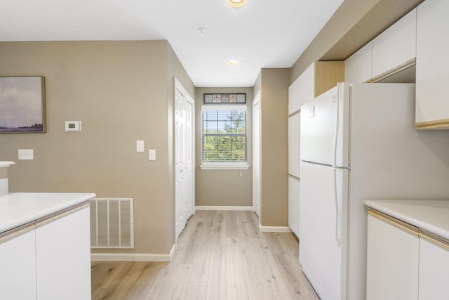 kitchen featuring white cabinets, white refrigerator, and light wood-type flooring