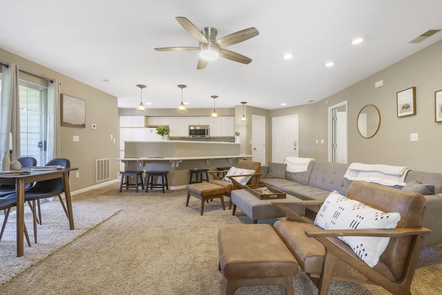 carpeted living room with ceiling fan