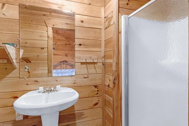 bathroom with wood walls, sink, and walk in shower