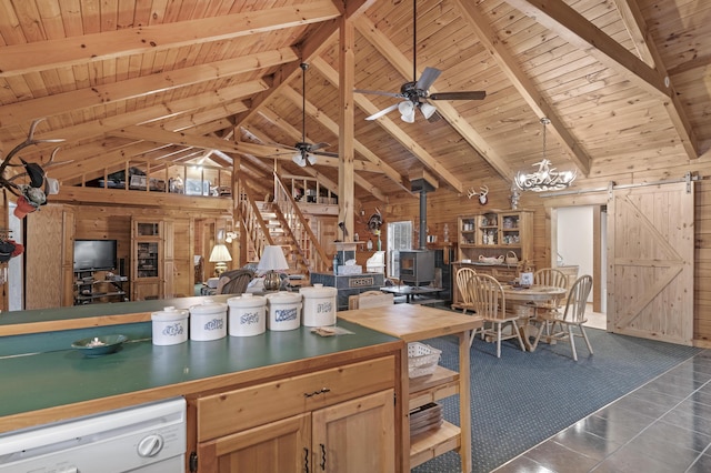 kitchen featuring dishwasher, a barn door, dark tile patterned flooring, and wooden walls