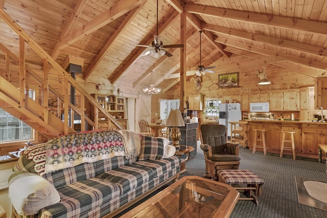 carpeted living room with ceiling fan with notable chandelier, wood walls, wooden ceiling, and beam ceiling