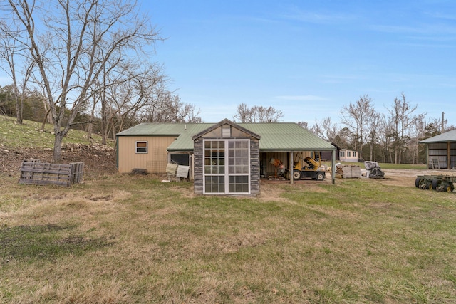 back of house featuring a lawn and an outdoor structure