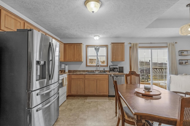 kitchen featuring a textured ceiling, decorative light fixtures, sink, and stainless steel appliances