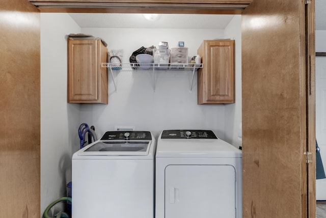 clothes washing area featuring cabinets and washing machine and dryer