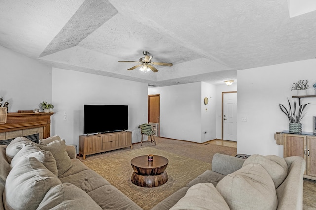 living room with a tile fireplace, a textured ceiling, and a raised ceiling