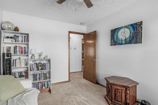 sitting room featuring ceiling fan, light colored carpet, and a textured ceiling