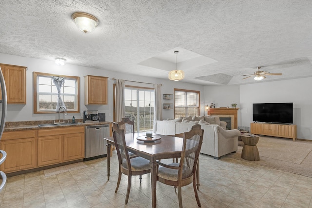 dining room with a textured ceiling, a tray ceiling, ceiling fan, and sink