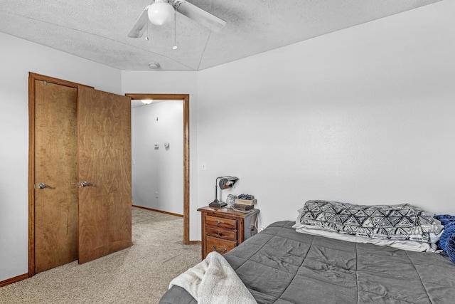 carpeted bedroom featuring ceiling fan and a textured ceiling