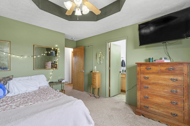 bedroom featuring connected bathroom, ceiling fan, light colored carpet, and a textured ceiling