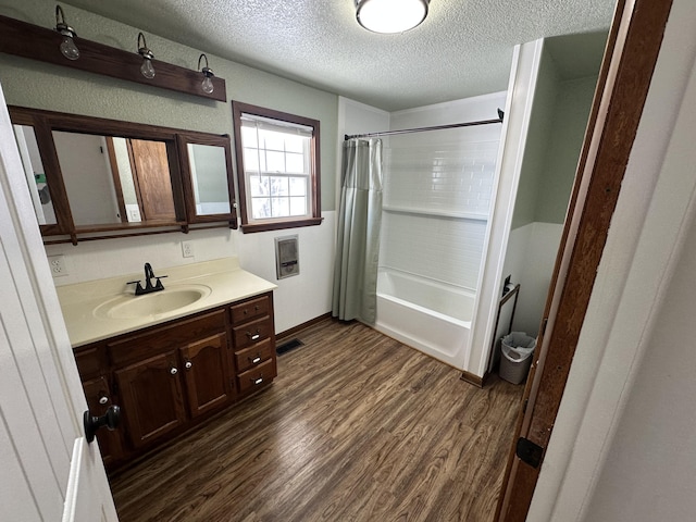 bathroom with wood-type flooring, vanity, a textured ceiling, and shower / tub combo with curtain