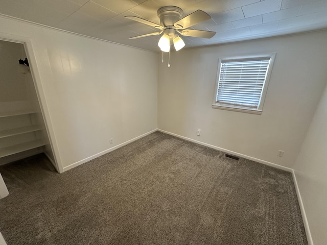 spare room with dark colored carpet, ceiling fan, and crown molding