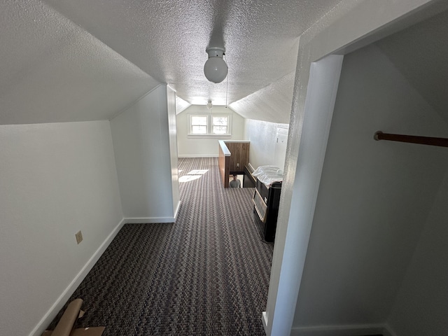 additional living space featuring dark carpet, a textured ceiling, and vaulted ceiling