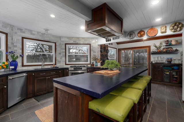 kitchen featuring wall chimney exhaust hood, stainless steel appliances, wood ceiling, a kitchen island, and sink