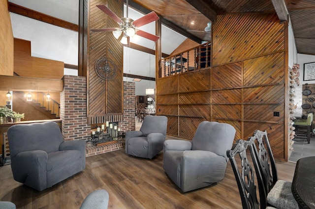 living room featuring wood-type flooring, beamed ceiling, ceiling fan, wooden walls, and high vaulted ceiling