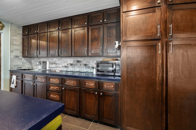 kitchen with sink, dark tile patterned flooring, decorative backsplash, and dark brown cabinetry