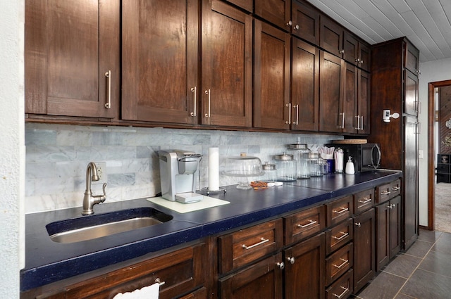 kitchen featuring sink, dark tile patterned floors, decorative backsplash, and dark brown cabinetry