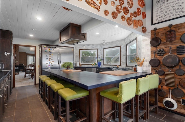 kitchen with wood ceiling, a breakfast bar area, appliances with stainless steel finishes, sink, and dark brown cabinets