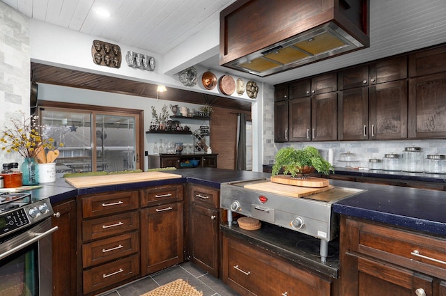 kitchen featuring stainless steel range, light tile patterned floors, premium range hood, dark brown cabinetry, and beam ceiling