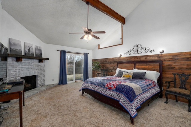 bedroom with carpet, vaulted ceiling with beams, ceiling fan, a fireplace, and access to exterior