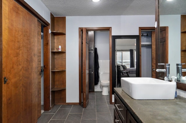 bathroom featuring a textured ceiling, vanity, and toilet