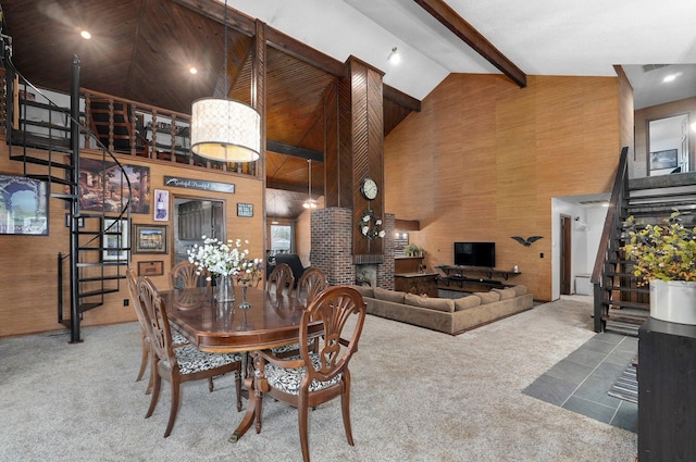 dining room featuring wood walls, high vaulted ceiling, carpet flooring, a fireplace, and beamed ceiling