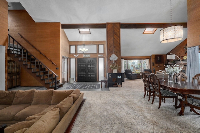 living room featuring wood walls, carpet, a notable chandelier, high vaulted ceiling, and beam ceiling